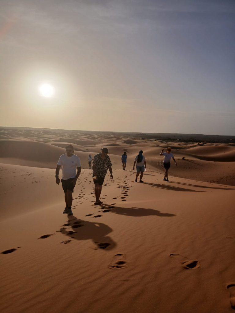 Voyageurs marchant sur les dunes de Merzouga au coucher du soleil dans le désert du Sahara