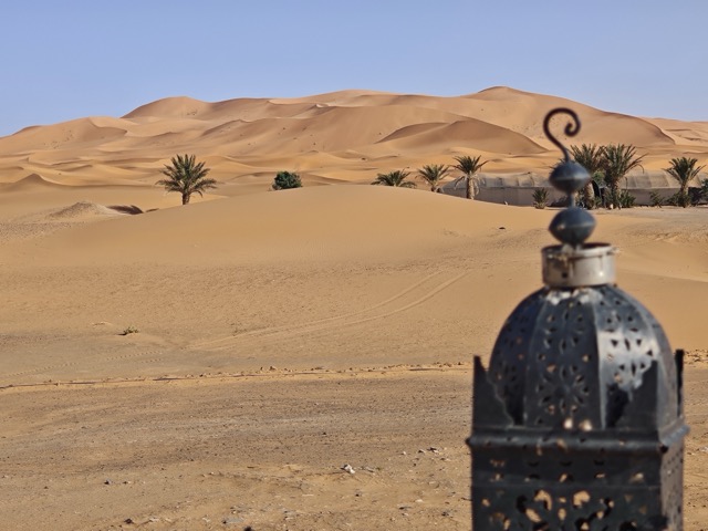 Lanterne marocaine traditionnelle surplombant les dunes du désert et les palmiers à Merzouga